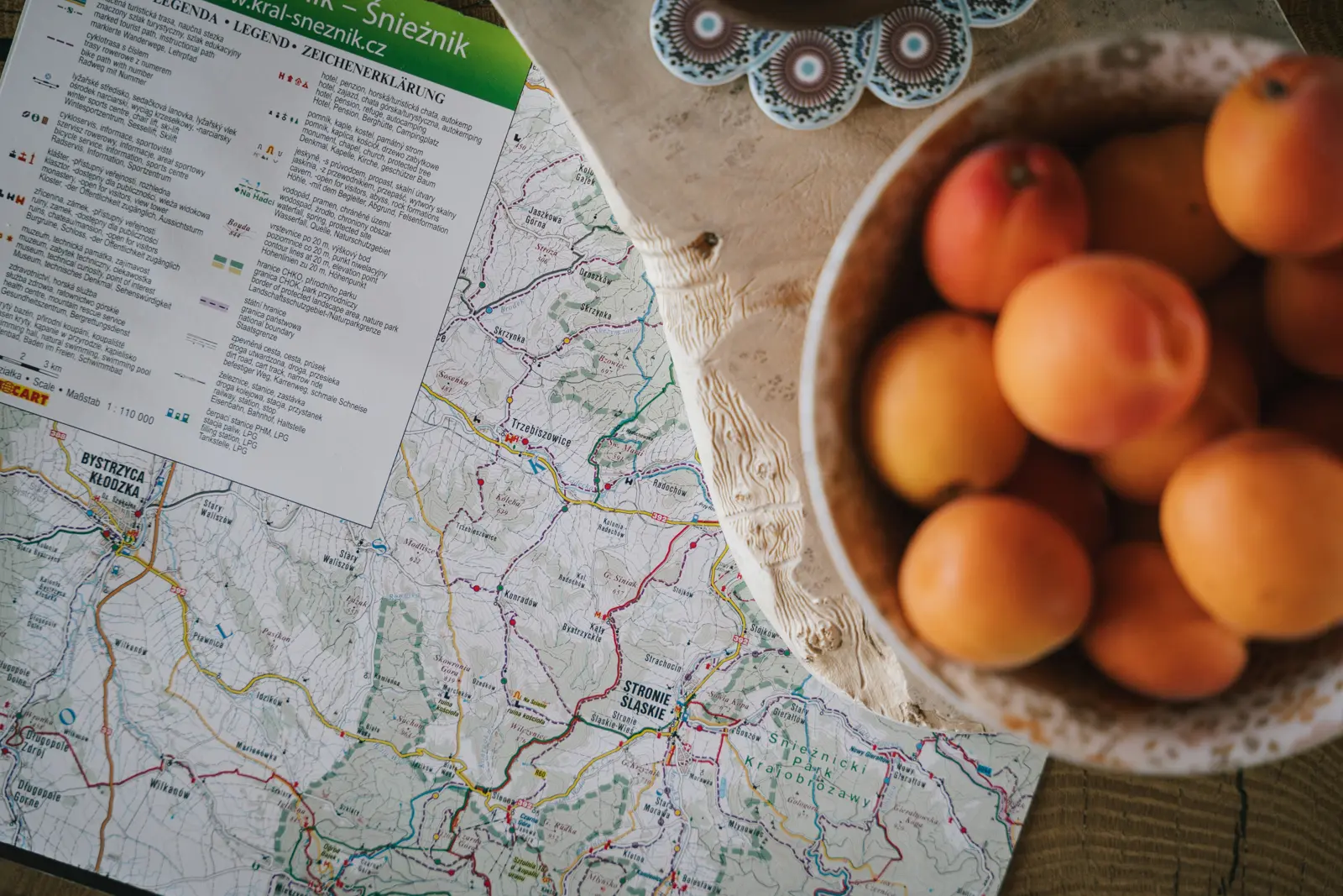Mapa szlaków Gór Bystrzyckich i misa moreli na stole